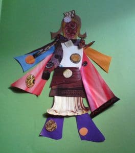 A paper collage figure with a mask-like face, wearing a colourful outfit with red, orange, and blue sleeves, purple trousers, and circular patterns, set against a green background.