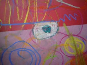 Colourful crayon and chalk scribbles on a red and pink surface with swirls, lines, and a central teal and white oval shape.