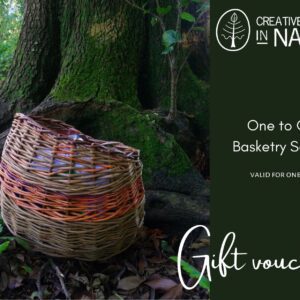 A woven basket sits on the ground next to a tree; text alongside advertises a one-to-one basketry session gift voucher from Creative Journeys in Nature.